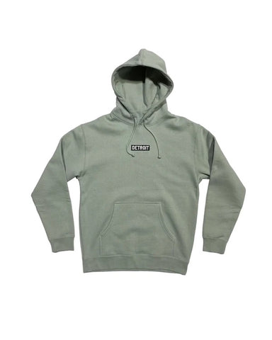 Ink Detroit Spirit of Detroit Hoodie.  Sage green, drawstring hood, kangaroo pocket.  Black patch with "Detroit" embroidered in white thread centered on chest.