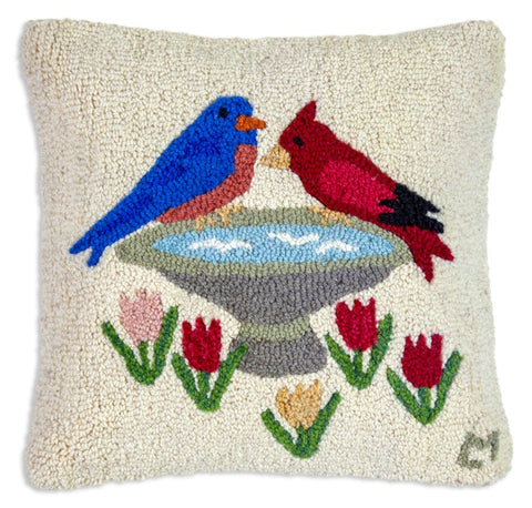 Cream hooked wool pillow featuring a blue bird and cardinal perched upon a bird bath with tulips below.