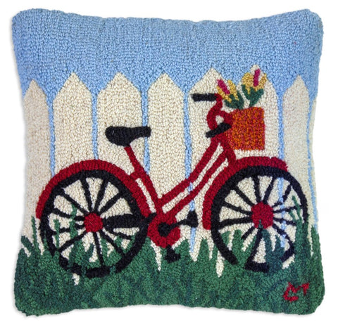 Hooked wool pillow featuring a red bicycle against a white picket fence.