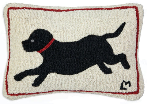 Cream hooked wool pillow with a red border featuring a black lab in a red collar running.
