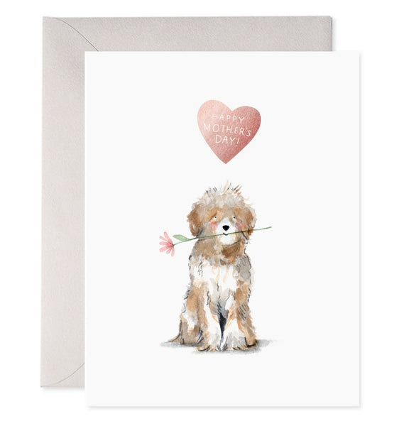 An adorable shaggy pup holds a flower in its mouth. A pink heart above reads "Happy Mother's Day!"
