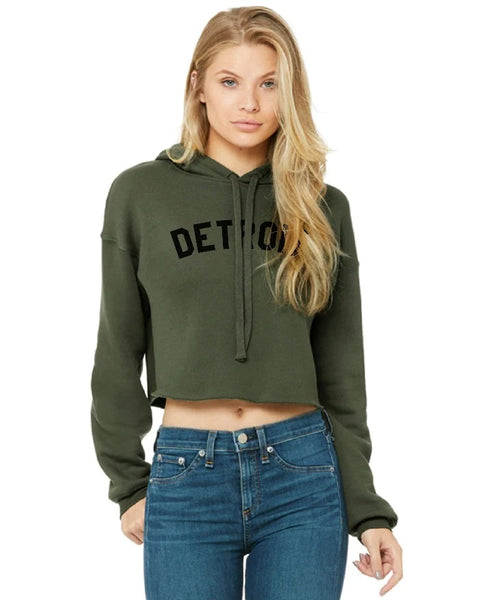 Ink Detroit Cropped Hoodie in green. Long sleeve, hooded sweatshirt in army green color with "Detroit" pritned across the chest. Cropped length with raw, rolled hem.
