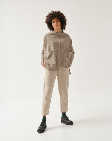 Funnel neck tunic sweater in heathered beige. Oversized fit, asymmetrical hem, large patch pockets on front, long sleeves.