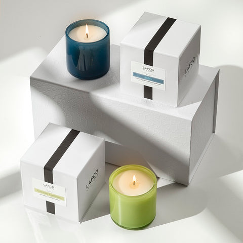 Two Lafco candles, one black and one green, displayed in an artistic yet simplistic white background.