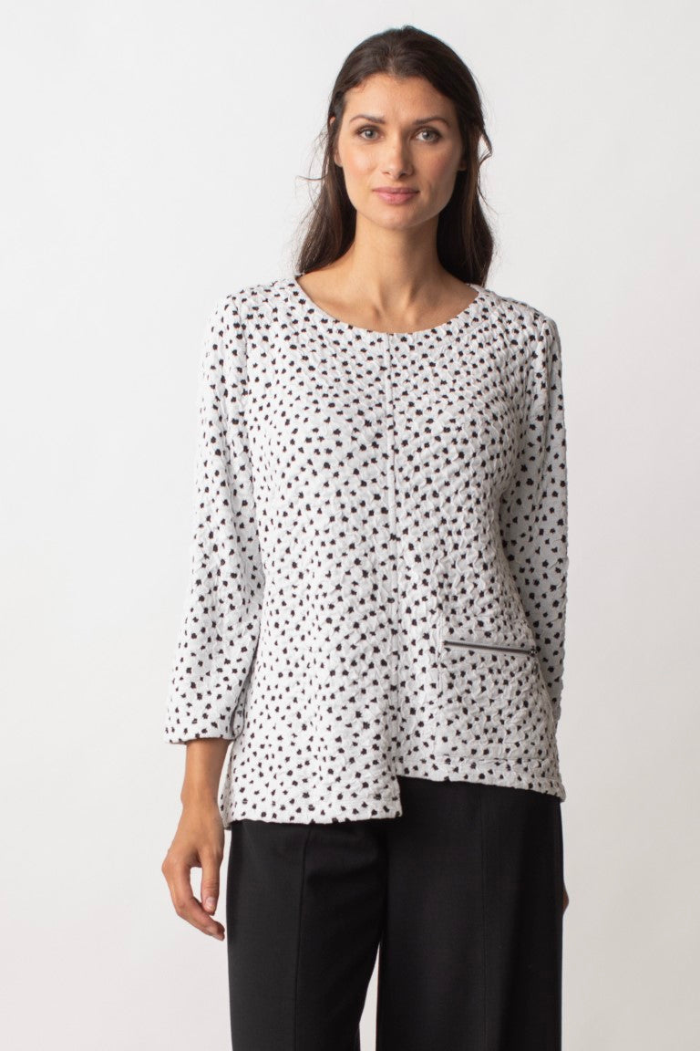 Liv by Habitat Speckled Dot Pullover in white. White tunic top with black dots scattered throughout.  Round neck, cropped sleeves, asymmetrical hemline, zuppered pocket on front.