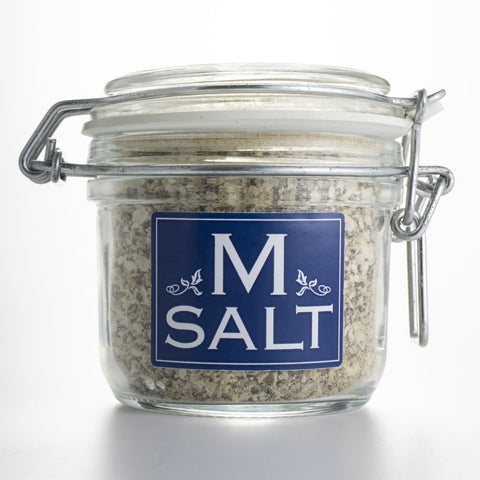 Glass salt jar with a blue tag that says M Salt.