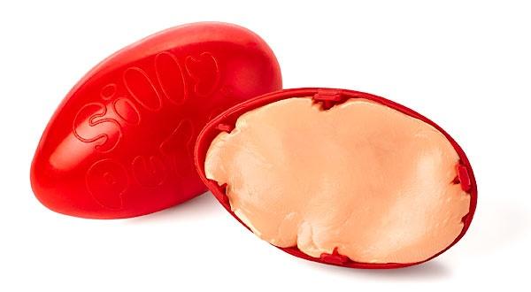Red plastic egg opened up with light pink silly putty inside.